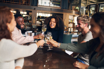 Friends celebrating with wine in bar - obrazy, fototapety, plakaty