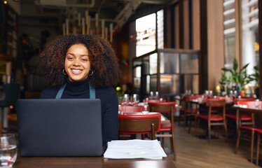 Portrait of cheerful restaurant owner with laptop