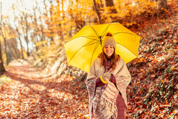Woman holding an umbrella walking down the autumnal forest path