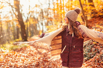 Woman spinning in circles while walking through forest in autumn