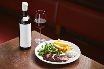 Bottle of red wine and steak in restaurant