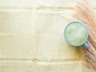 Matcha tea latte morning drink on yellow cloth with pampas