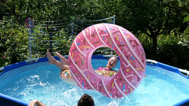 Happy girls have fun chilling and floating on donut floats in swimming pool in summer, floatation