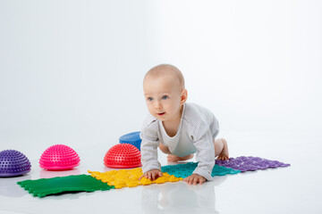 Cute baby boy crawling on a white background with orthopedic mat and hemisphere