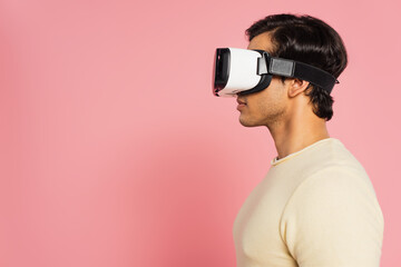side view of young man in vr headset isolated on pink