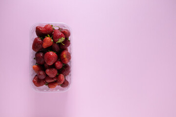 fresh strawberries  in plastic  food container on pink background. Concept of Recycling plastic and ecology. zero waste. Copy space