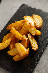Baked potatoes on slate board on grey table