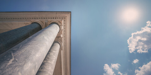 Antique colonnade with roof in classic style against blue sky
