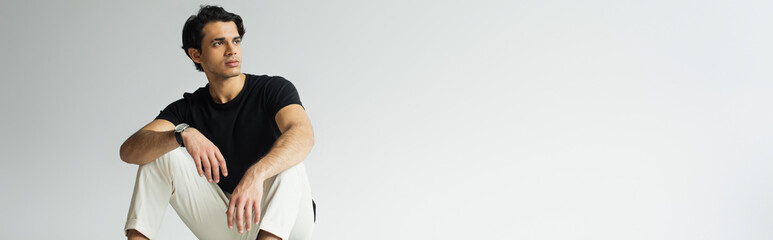 young man in black t-shirt sitting on grey, banner