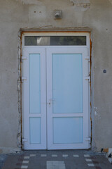New quality plastic door secured with yellow foam and inserted into an old stone wall, unfinished improvement work.