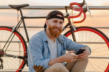 handsome bearded man traveling with bicycle in morning sunrise by the sea