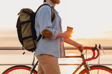 handsome bearded man traveling with bicycle in morning sunrise by the sea