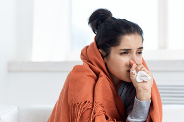 woman covered with a blanket at home drinking medicine