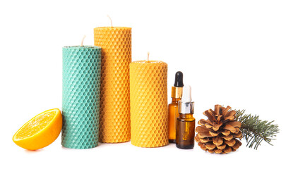 Composition with handmade wax candles and bottles of essential oil on white background