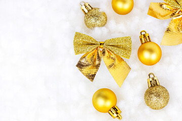 Fototapeta na wymiar Bright golden and yellow Christmas decorations (ribbons, baubles, ornament) flat lay on white artificial snow background with copy space. Christmas and New Year holiday celebration concept.