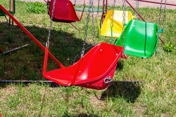 Bright colorful seats for children swing attraction in the amusement park in summer.