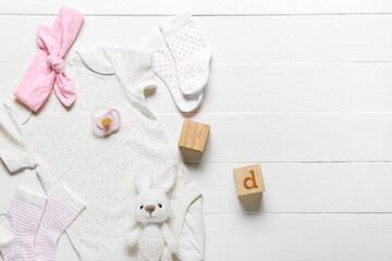 Composition with baby clothes, toys and accessories on light wooden background