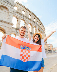 happy beautiful couple in front of coliseum in Pula Croatia with croatian flag