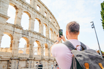 man taking picture on the phone of coliseum in Pula, Croatia