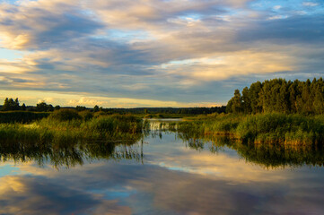 Fototapeta na wymiar Beautiful calm blue landscape at the sunset of the lake. Reflection of clouds in the water