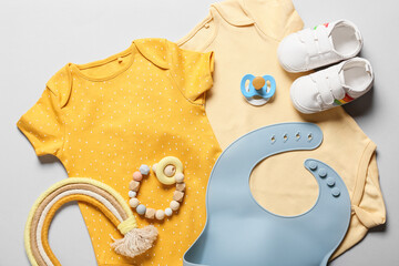 Baby clothes, shoes, toy and accessories on light background, closeup