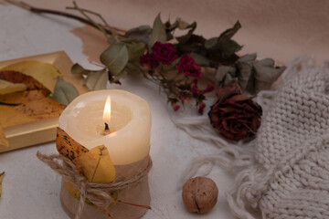 Autumn vintage still life with fallen leaves, candles and a knitted blanket. Autumn atmosphere concept