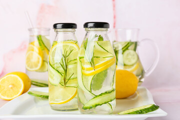 Bottles with cucumber lemonade on light background
