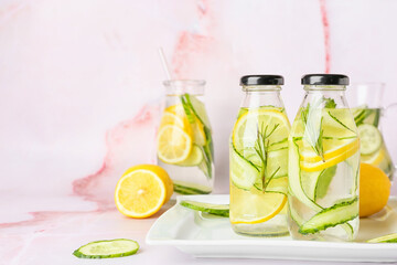 Bottles with cucumber lemonade on light background