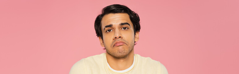 confused man showing shrug gesture isolated on pink, banner