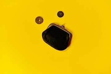 czarna portmonetka i monety na żółtym tle