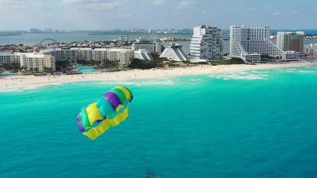 Camera rotates to show parasailer near Cancun's resorts