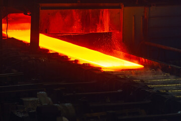 Incandescent hot rolled steel sheet in soft focus on a conveyor belt. Metallurgical production, hot...