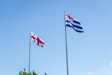 National flags of Georgia and Adjara on blue sky background
