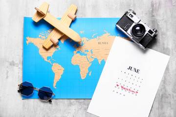 Calendar, world map, photo camera, sunglasses and wooden toy on grunge background