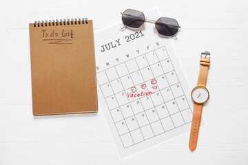 Calendar, to-do list and female accessories on light wooden background