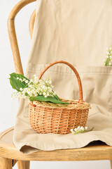 Fototapeta na wymiar Basket with lily-of-the-valley flowers on chair