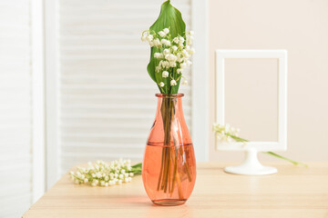 Vase with lily-of-the-valley flowers on table in room