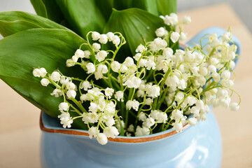 Vase with lily-of-the-valley flowers on table at home, closeup