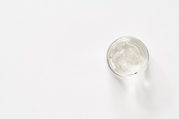Aloe vera gel in a cosmetic glass jar on bright background, top view. Healthy skin product.