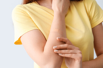 Young woman with applied medical patch against grey background, closeup
