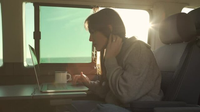 Traveling woman working on laptop in van