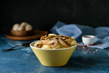 Bowl with tasty mashed potatoes and mushrooms on color background