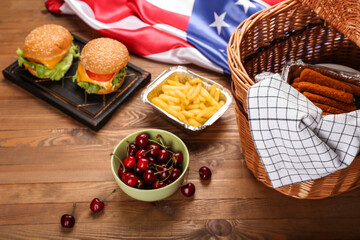 Traditional American food with picnic basket and flag on wooden background