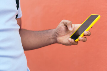 Young man with smart phone next to a red wall