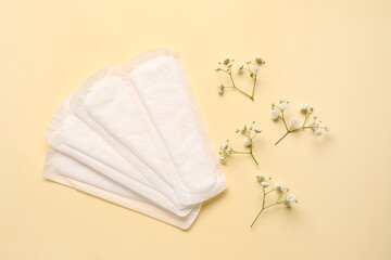 Fototapeta na wymiar Menstrual pads and flowers on color background