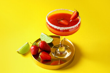 Glass of strawberry daiquiri cocktail, lime and berries on color background