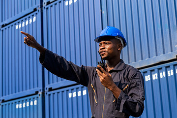  african amarican man working control loading freight containers at commercial shipping dock. cargo...
