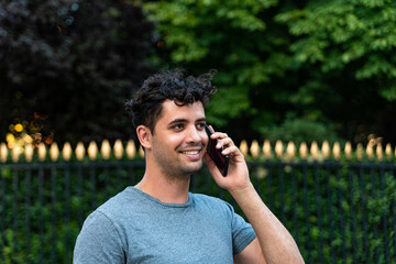 Young latin man in the park talking by mobile phone.