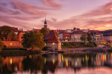 Fototapeta premium Amazing view of Maribor Old city, medieval water tower on the Drava river before sunrise, Slovenia. Scenic cityscape with cloudy sky and reflection, travel background for wallpaper or guide book