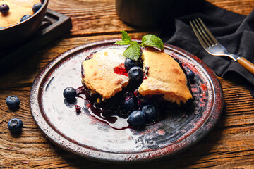Plate with pieces of blueberry cobbler on wooden background, closeup